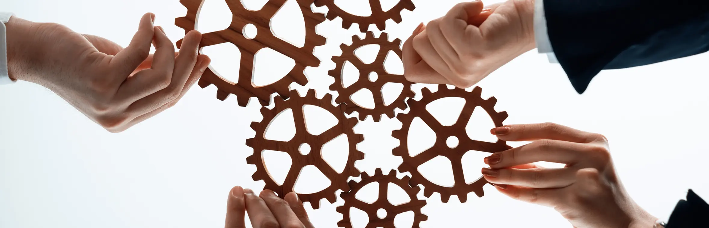 Hands holding cogs, linking them together